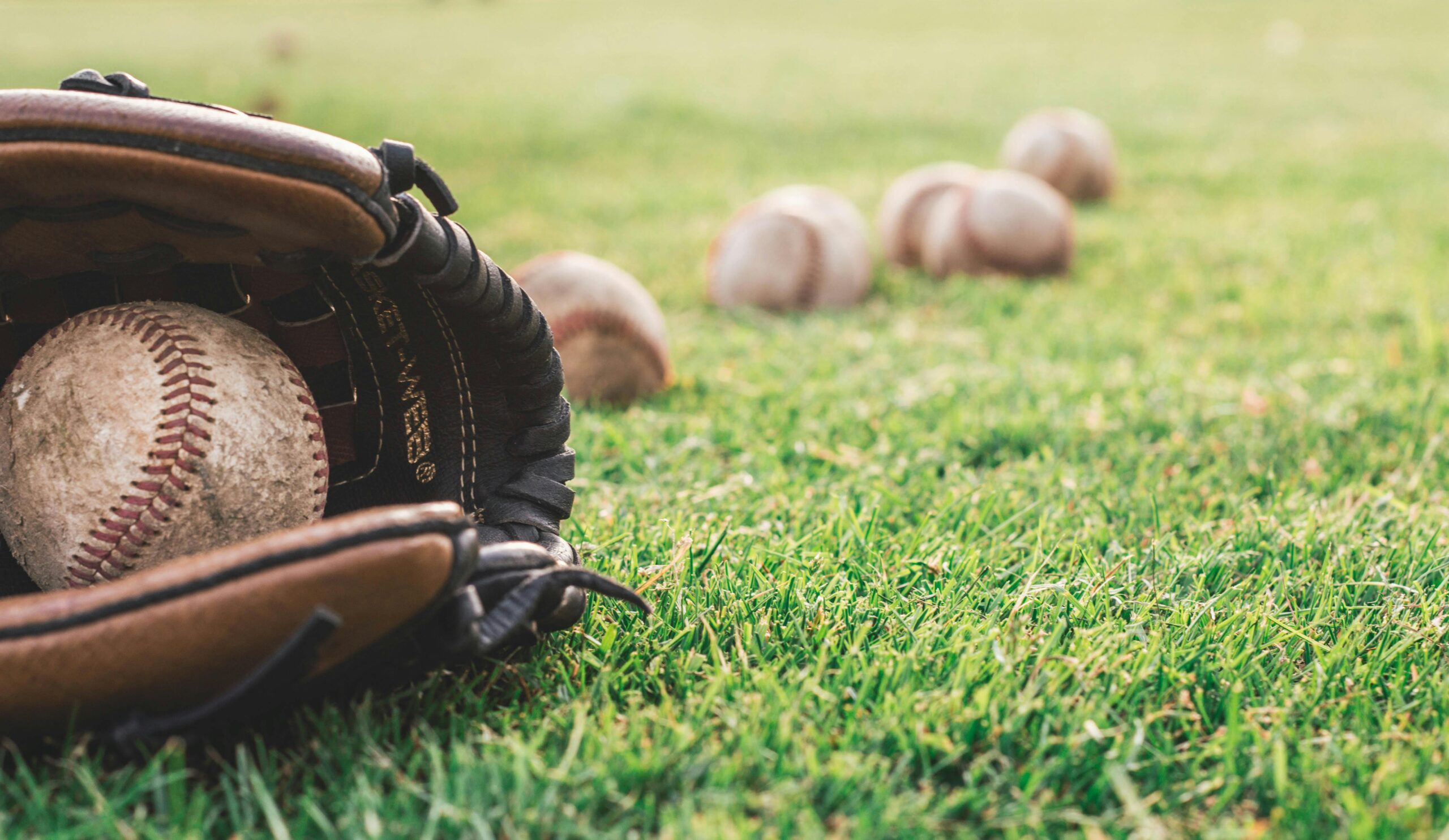 Baseball glove with baseballs on field